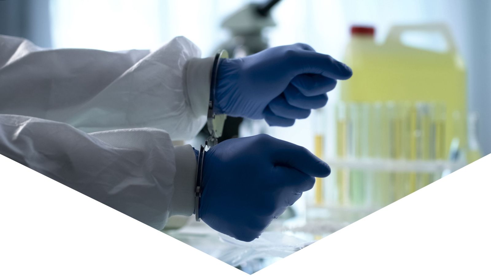 Harbour Hazmat provides clandestine lab services, lab worker hands in handcuffs with blue gloves on, lab equipment in the background